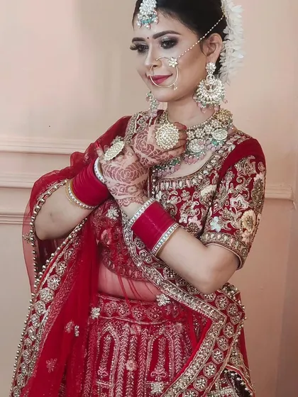 A happy bride trying on a classic red embroidered lehenga at my studio. You can see how the full set, including the nath and maang tikka, comes together.