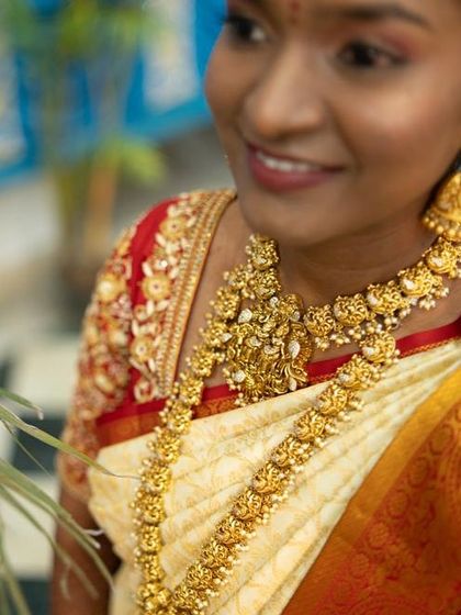 Our bride Sushma looks radiant on her wedding day. She is wearing a beautiful antique-finish temple jewellery set that perfectly complements her cream and red saree.