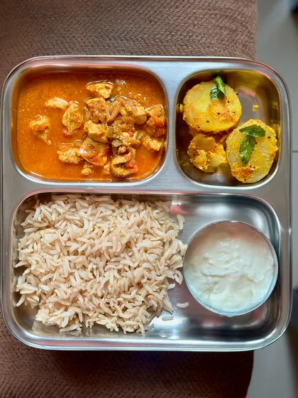 A non-vegetarian meal of brown rice, chicken curry, and boiled potatoes. This is a simple, high-protein meal that is great for post-workout recovery.