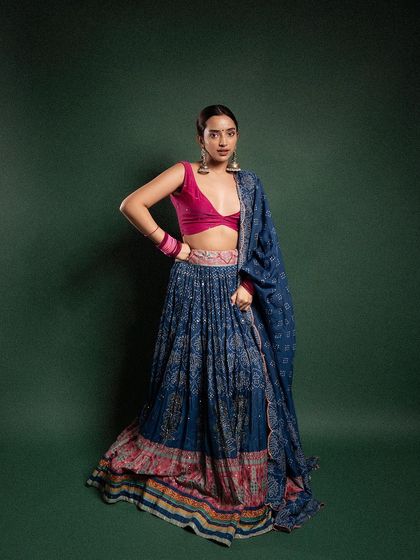 A confident, full-length pose against a solid green background. This allows the colors and patterns of the traditional outfit to stand out, making it a strong shot for a lookbook.