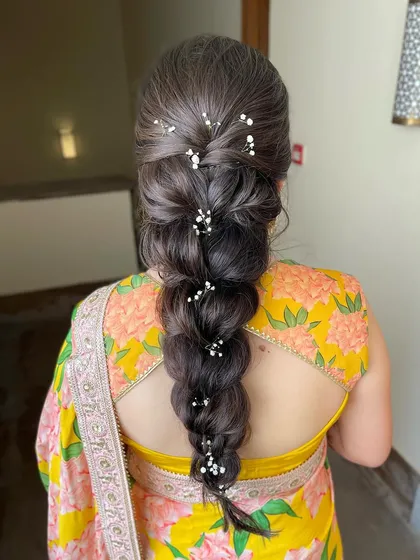 An intricate, voluminous braid decorated with delicate baby's breath. This is a soft and romantic take on a traditional braid, perfect for a Mehendi or Haldi.