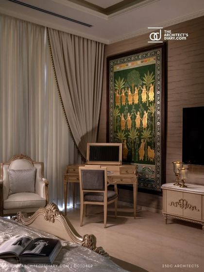 This bedroom corner features a classic writing desk and an ornate armchair, set against a backdrop of rich textiles and a traditional Pichwai painting. It is a quiet nook for reflection, blending Indian artistry with European elegance.