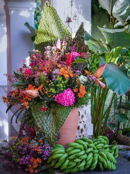 A large floral arrangement for a Pellikuthuru ceremony, featuring a mix of tropical flowers and woven coconut leaves.