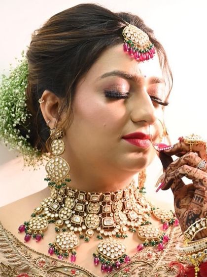 A close-up of our stunning bride wearing a detailed pachi kundan choker set with ruby-colored bead drops. The matching maang tikka and nath complete this traditional yet glamorous wedding look.