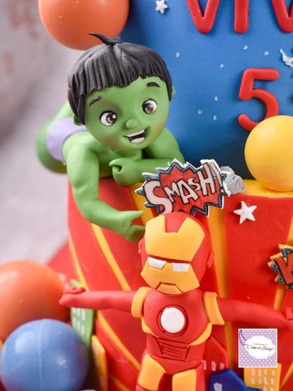 Here's the Hulk smashing through the side of the cake, with a tiny Iron Man below. It took four days to create all the detailed, handmade elements for this superhero-themed cake.