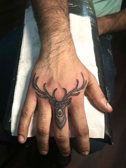 A close-up of the deer finger tattoo, showcasing the fine lines in the antlers and the delicate shading on the face.