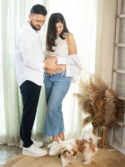 The whole family is getting ready for the new arrival, including their furry friend. This shot captures a lovely moment with the couple and their cute dog during a casual studio session.
