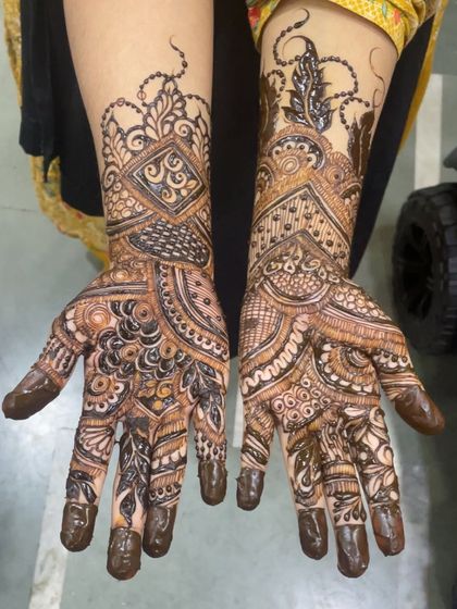 A beautiful example of a full hand bridal design with a mix of geometric and floral elements. The fingertips are fully dipped for that deep, traditional stain.