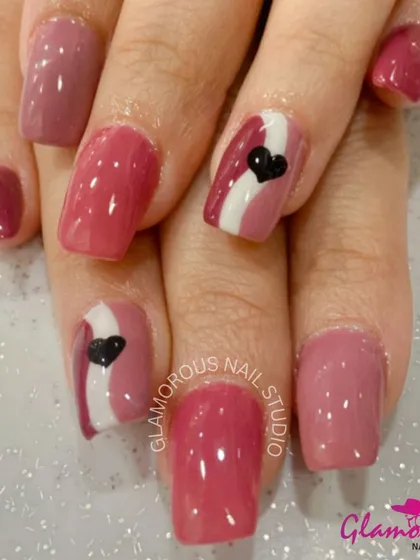 A chic design in shades of pink, with accent nails featuring a white stripe and a single black heart for a modern, graphic look.