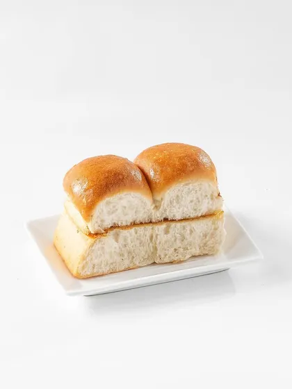 Soft, buttery pav buns, the essential partner to Pav Bhaji. This clean shot focuses on the bread's texture and golden-brown top, designed to complement the main dish in a menu layout.