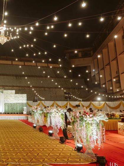 The reception venue just before the guests arrive. The warm string lights, cascading floral arrangements, and perfectly aligned seating create a sense of anticipation for the grand celebration ahead.