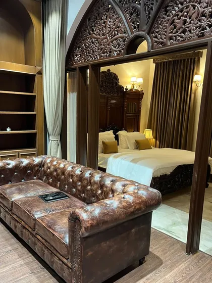 I love blending classic Indian aesthetics with luxurious comfort. This bedroom showcases our expertise in sourcing and integrating timeless pieces, like this intricately carved wooden headboard and archway, to create a space that feels like a royal heritage suite.