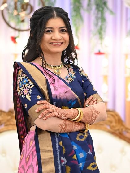 A smiling portrait of a guest, her arms crossed to show off the lovely henna stain.