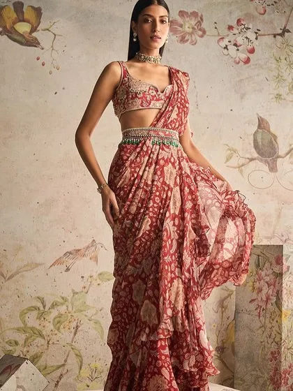 A red printed ruffle saree with an embellished belt. This is a fun and playful take on the classic saree, perfect for a sangeet or cocktail party.