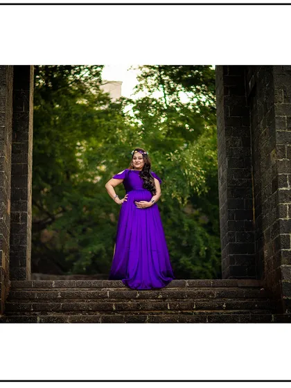 A powerful solo portrait framed by a stone archway, with the mom-to-be in a vibrant purple gown.
