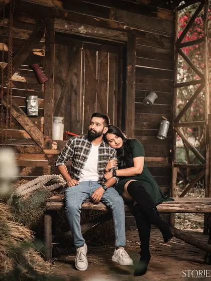 A relaxed portrait in a rustic, barn-like setting. The warm lighting and wooden textures create a cozy and intimate atmosphere for this couple's pre-wedding shoot.