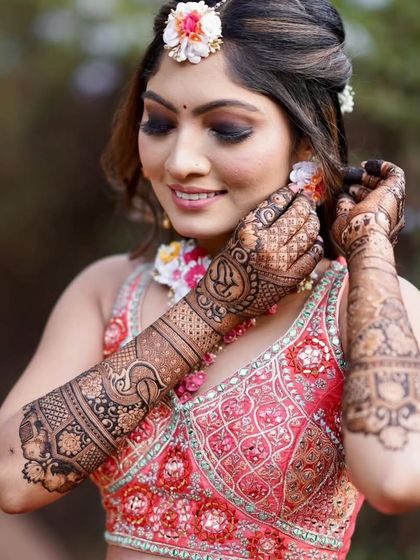 A bride adjusting her earring, giving a beautiful view of her back-hand mehandi design.