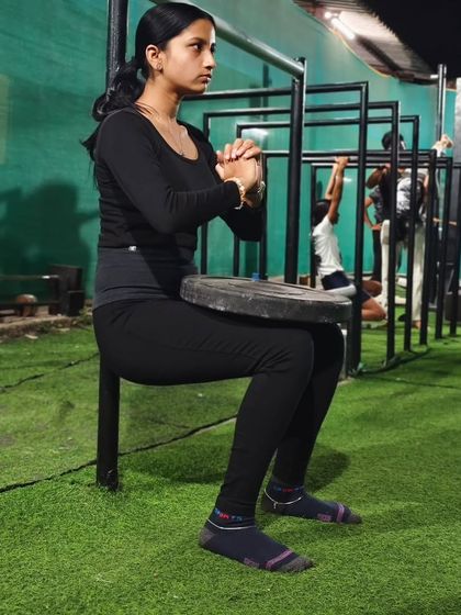 Using a weight plate to increase the intensity of a wall sit. We constantly find ways to challenge our members and drive progress.