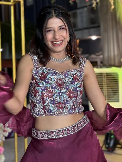 A close-up on the beautifully detailed blouse, featuring multicolour threadwork and sequins. It’s the perfect complement to the dramatic maroon ruffled skirt.