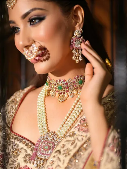 A candid shot capturing the bride's smile and the beautiful details of her earrings and necklace. The makeup is soft and romantic, a perfect match for the moment.