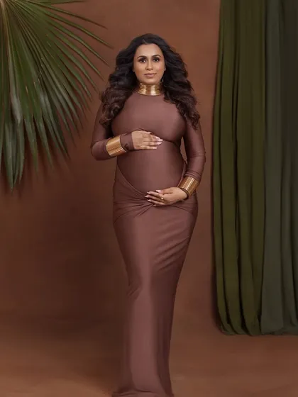 A frontal portrait that is both powerful and gentle, as she holds her bump with both hands.