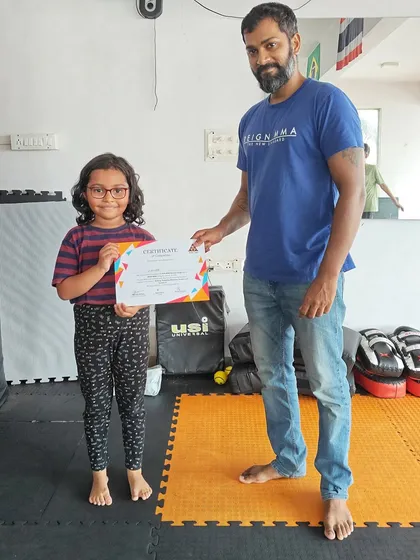 Look at that proud smile. This young student is thrilled to receive her certificate, marking the end of a successful and fun-filled MMA summer camp.