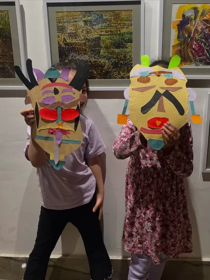 Getting creative with paper crafts. These two kids made their own expressive masks, cutting and pasting colorful paper to build unique characters.