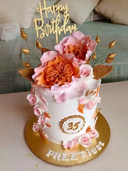 An elegant 35th birthday cake decorated with large, handcrafted wafer paper flowers and delicate pink sugar roses.