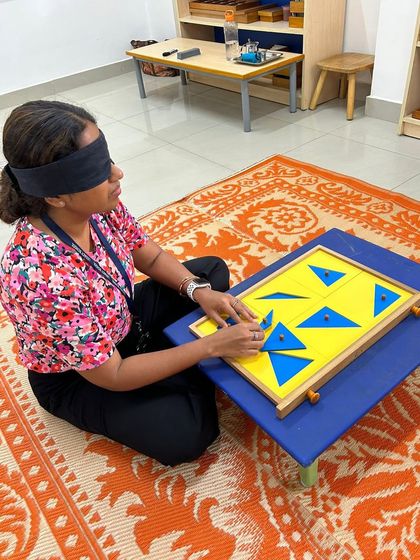 An educator at Legacy School explores the constructive triangles, blindfolded to focus on the stereognostic sense. Our workshops provide teachers with direct experience of the materials.