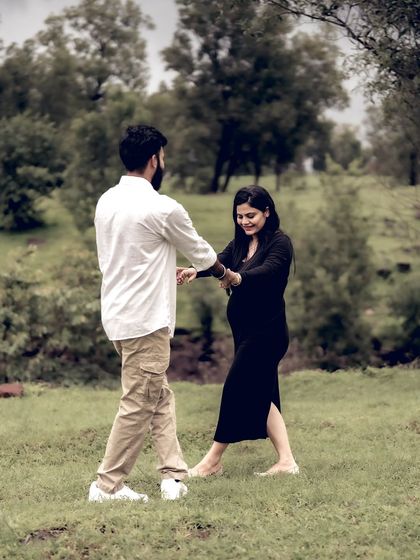 A playful moment of the couple dancing in a field, surrounded by trees. It’s a candid shot that shows their fun-loving relationship.
