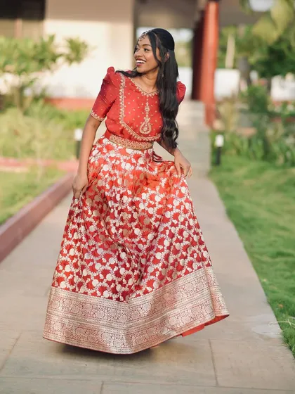 A candid shot of our client walking in her cherry red lehenga, showcasing its effortless grace.