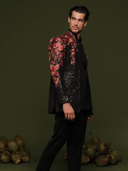 Make a bold statement with a designer Indo-Western piece. This professionally shot look features a black sequined jacket with vibrant floral embroidery on the shoulders, perfect for a sangeet or reception.