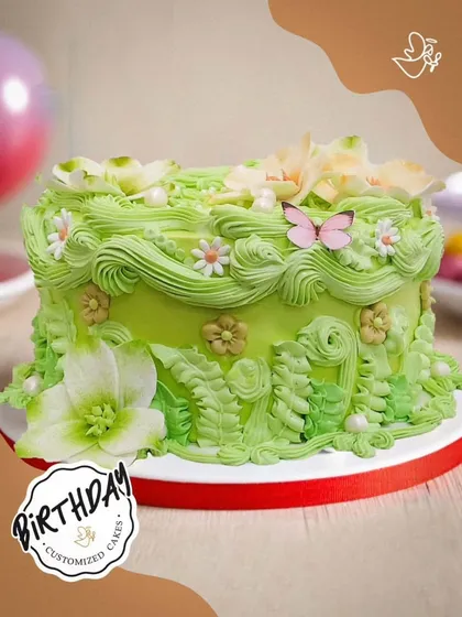 A blooming garden on a cake, this design features delicate green buttercream piping, sugar flowers, and a tiny pink butterfly for a touch of whimsy.