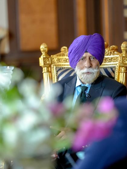 A candid moment with His Highness, where the quality of the suit's fit is apparent even when seated. Comfort and elegance are not mutually exclusive in our designs.