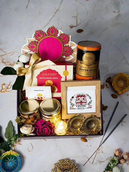 A closer look at the details in our luxury Diwali hamper. This arrangement includes traditional motichoor ladoo, jars of premium nuts, wafer sticks, fragrant incense, and hand-painted diyas, all centered around a personalized photo frame to make your gift truly unique.