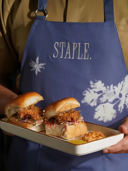 A server presenting a tray of crispy chicken sliders, highlighting the dish and the restaurant's professional service.