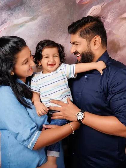 A happy family of three shares a laugh during their son's first birthday photoshoot.