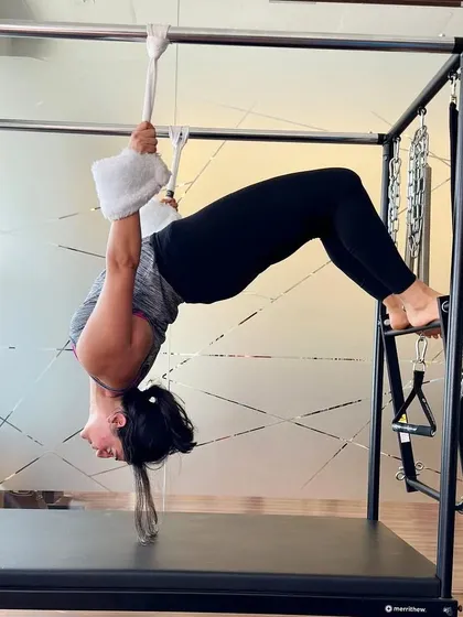 A client performs a deep backbend on the Cadillac, a testament to her hard work and the trust she has in her body and the equipment.
