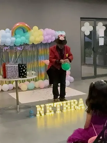 A magician performing balloon modelling at a rainbow-themed party. We provide entertainment that complements your chosen theme and keeps the young guests delighted.