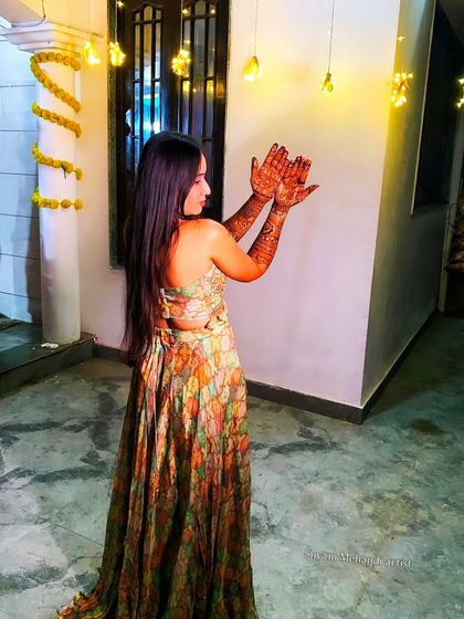 A creative shot of the bride showing her mehandi against a backdrop of festive lights.
