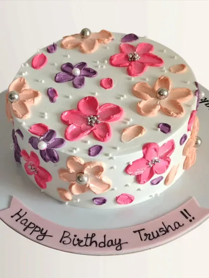 A birthday cake adorned with colorful, impressionistic flowers created with a palette knife technique. This gives the cake a unique, artistic texture.