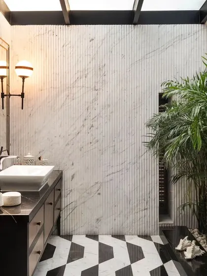 A close-up of the skylit bathroom, highlighting the interplay of natural light on the textured marble walls and the elegant vintage-style light fixtures.