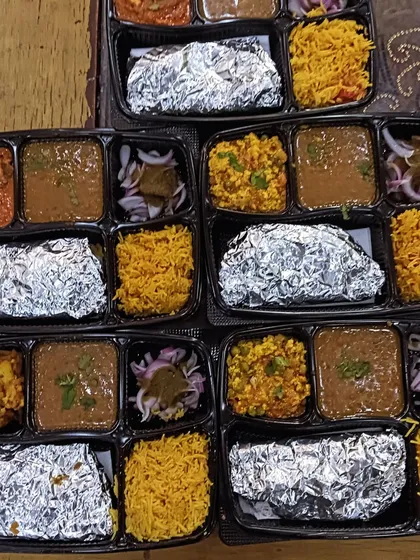 A variety of thalis prepared for a single event, including dishes like Paneer Bhurji, Chole, and Dal Makhni, all served with Tehri-style yellow rice.