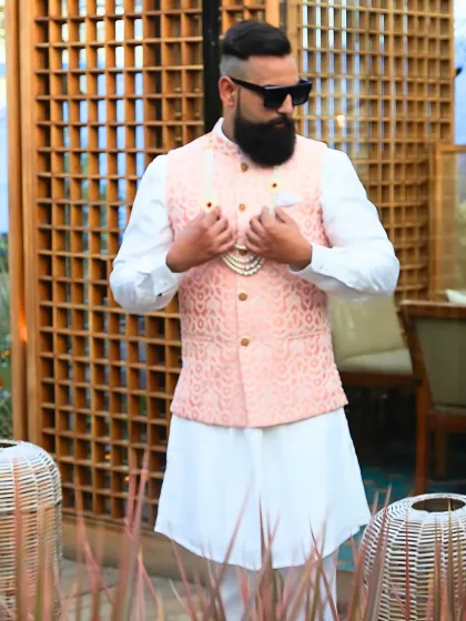 When subtle details speak volumes. This light peach brocade waistcoat, layered over a pristine white kurta, is an elegant choice for a wedding guest, offering a look that is both classic and fresh.