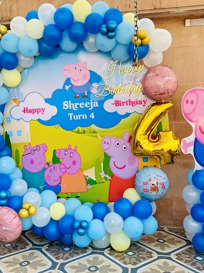 A delightful Peppa Pig themed birthday party for a 4-year-old. The setup includes a custom backdrop with Peppa and her family, character cutouts, and a blue and yellow balloon arch.