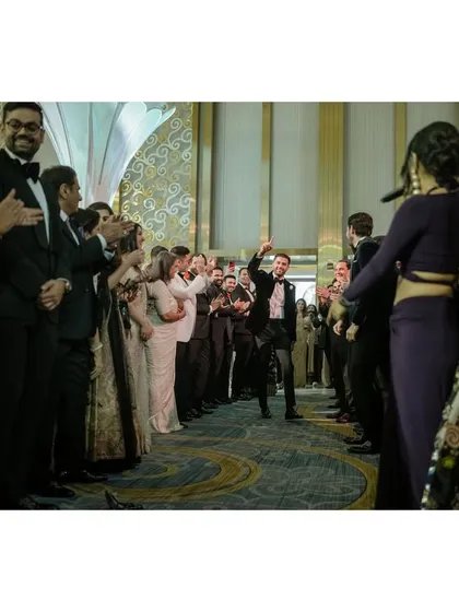 The sea of people parts for Raghav as he begins his surprise dance for Sanjana. This shot captures the anticipation and energy of a sangeet performance.