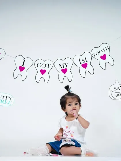 The whole family can get involved in celebrating, holding up fun signs like "Happy Teething" and "Say Cheese".