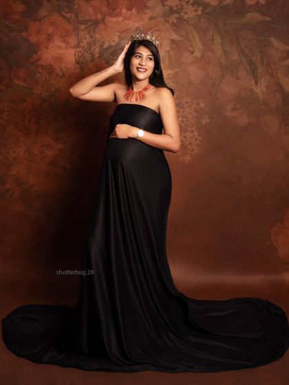 A confident and joyful portrait of a mom-to-be in a striking black satin gown. The crown adds a playful touch of royalty, celebrating her strength and beauty during pregnancy.