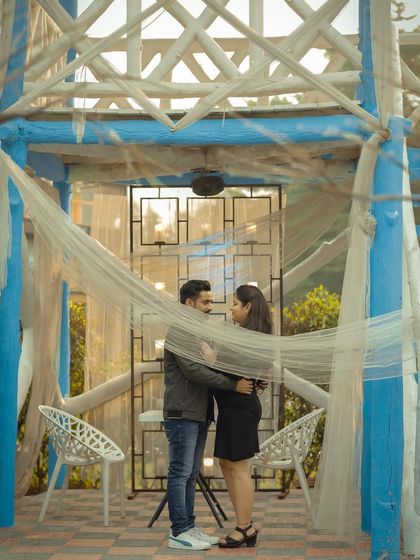 A romantic and intimate pre-wedding photo, framed by the architecture and soft netting of a gazebo.