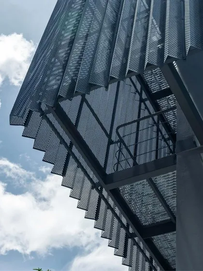 An upward view of the custom-folded perforated sheet metal facade at ICP Brunton Central. This lightweight "skin" was a key design move to update the building, improve its environmental performance, and create a memorable architectural identity.